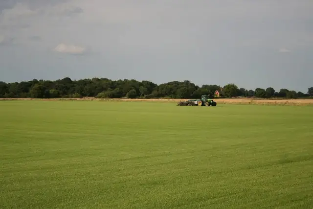 Tractor mowing a broad green lawn in the English countryside